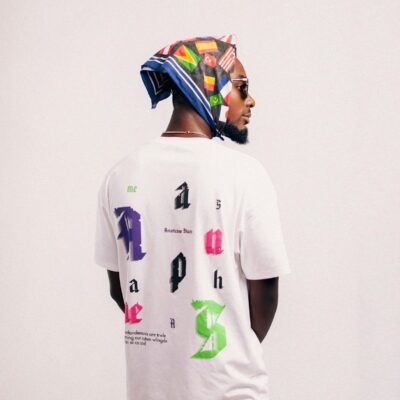 Stylish man wearing a graphic printed t-shirt and a colorful bandana with sunglasses.