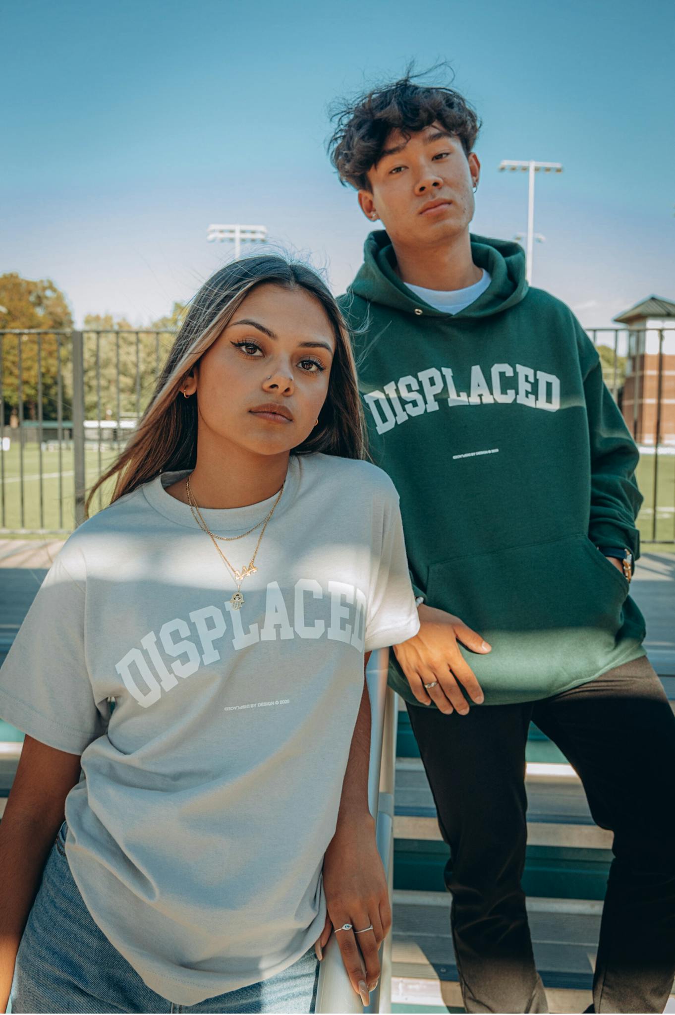 Young adults posing in casual streetwear outdoors, showcasing fashionable displaced shirts.